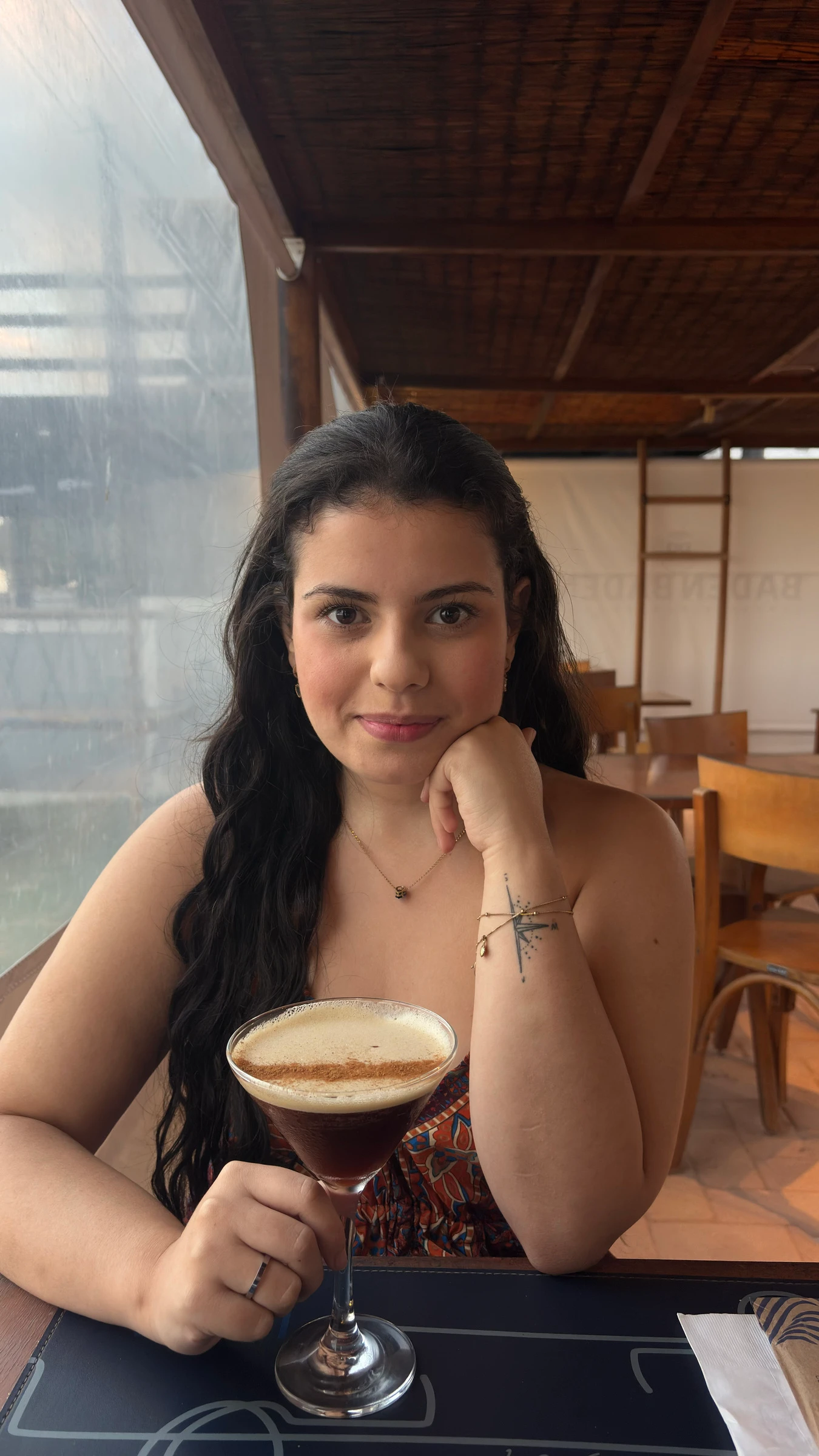 Melyssa Martins sentada à mesa de um café