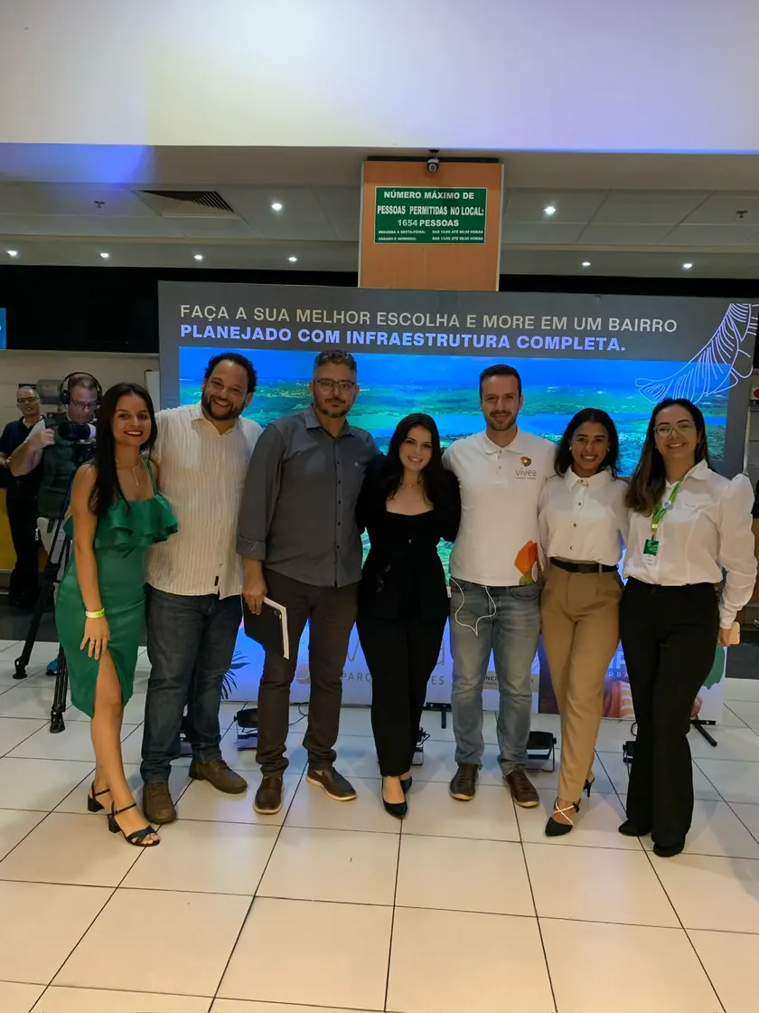 Equipe posando em frente ao banner do empreendimento